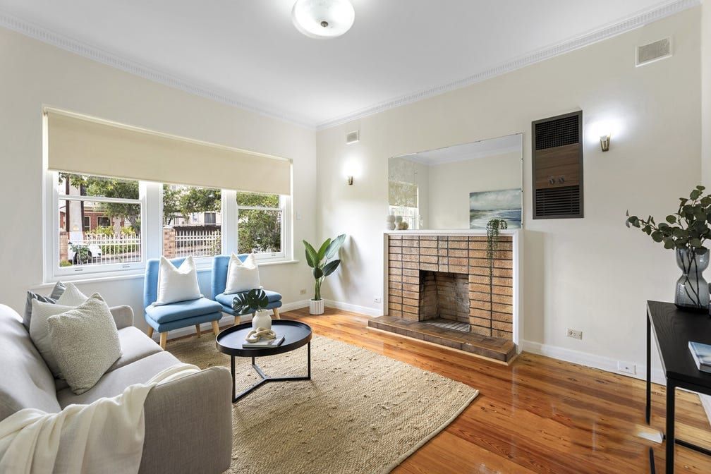 The lounge room at Colton Avenue, with polished timber floors and a brick fireplace