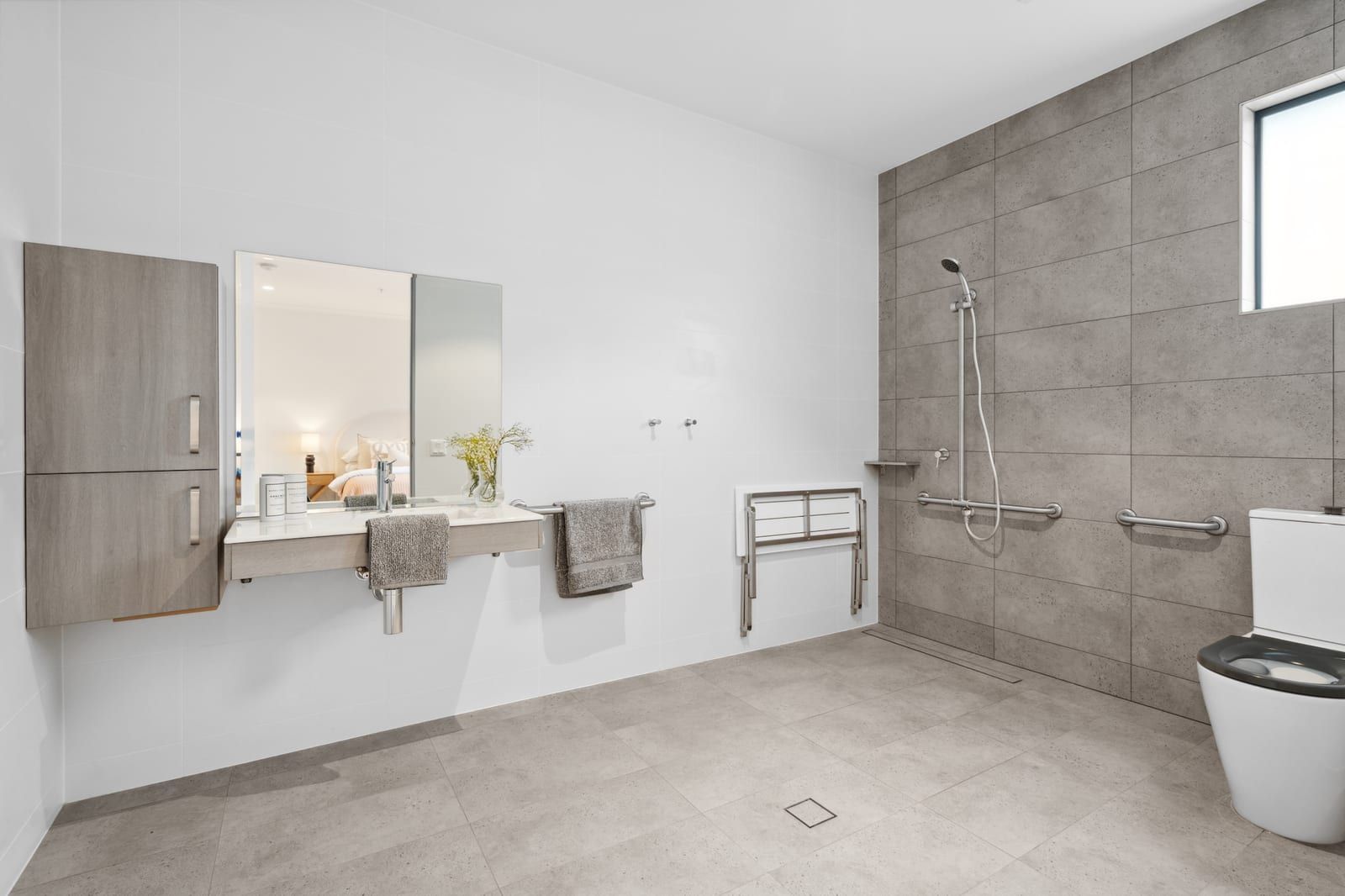 The bathroom at Wyndham Road, with a level-entry shower, grab rails and a fold-down seat